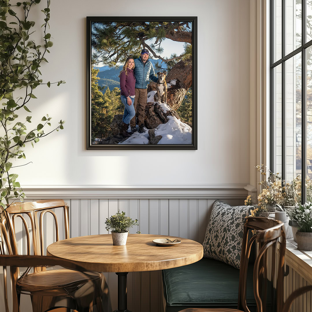 Framed Photo of a couple and their brindle dog in the snow during winter photoshoot. Photo is displayed on wall of kitchen eating nook with small table.