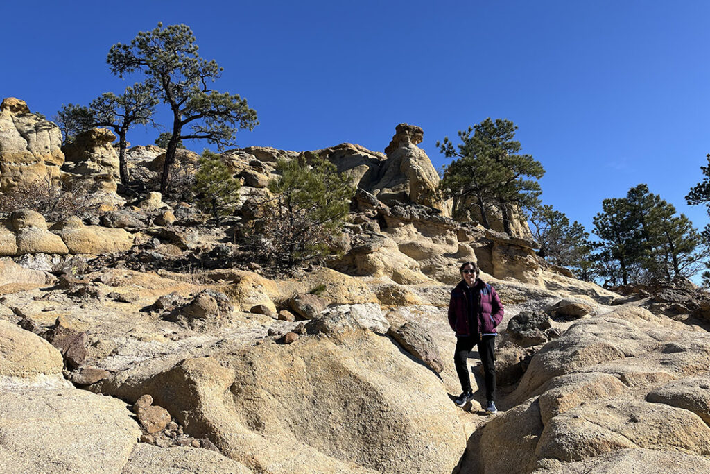 Woman standing on rocky trail with evergreens at Templeton Trail in Palmer Park in Colorado Springs